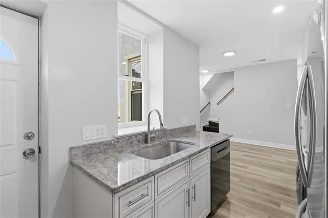 a kitchen with a sink granite counter tops and a wooden floor