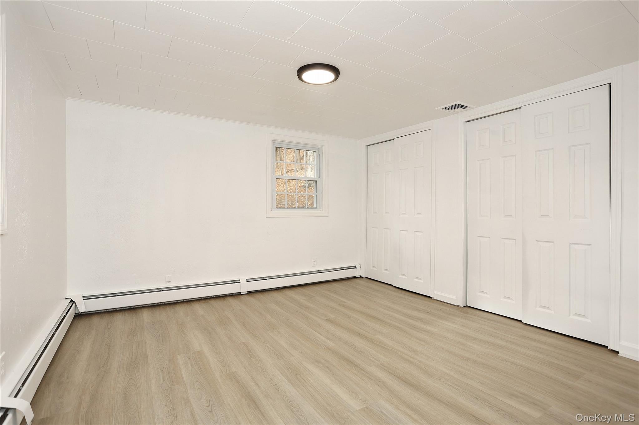 84 Pine Hill Road Chester, NY 10918 - Photo 18 of 18 Master bedroom featuring a baseboard heating unit, two closets, and light wood-style floors