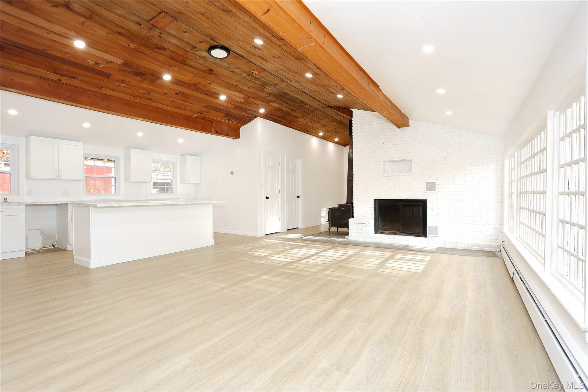 84 Pine Hill Road Chester, NY 10918 - Photo 9 of 18 Unfurnished living room featuring a baseboard heating unit, light wood finished floors, and a fireplace