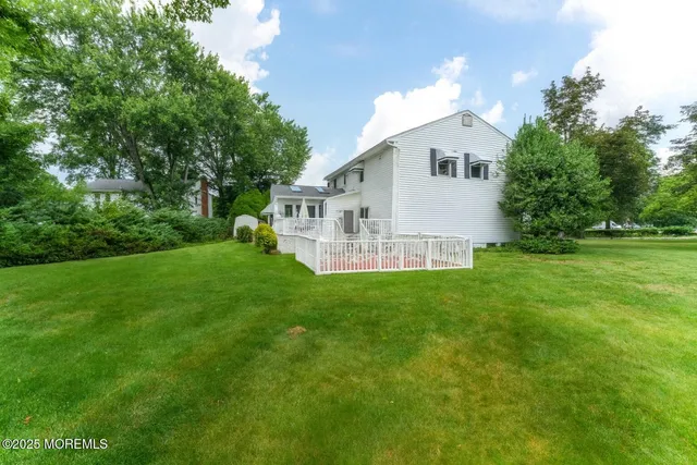 a view of a white house with a big yard and large trees
