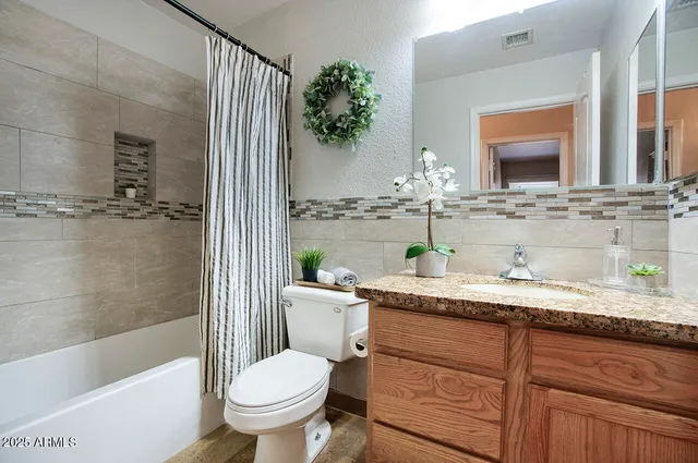 a bathroom with a granite countertop sink a toilet a mirror and bathtub