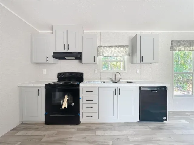 a kitchen with stainless steel appliances granite countertop a sink a stove and a refrigerator with wooden floors