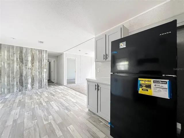 a view of an empty room with a kitchen and a window