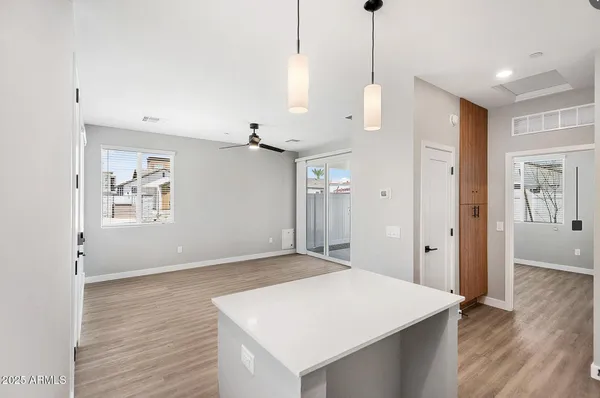 a view of an empty room with wooden floor and a ceiling fan