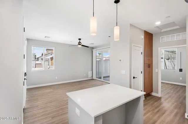 a view of an empty room with wooden floor and a ceiling fan