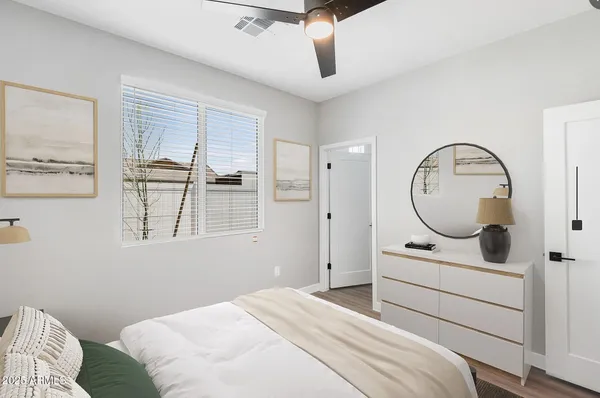 a bedroom with a bed a mirror and windows