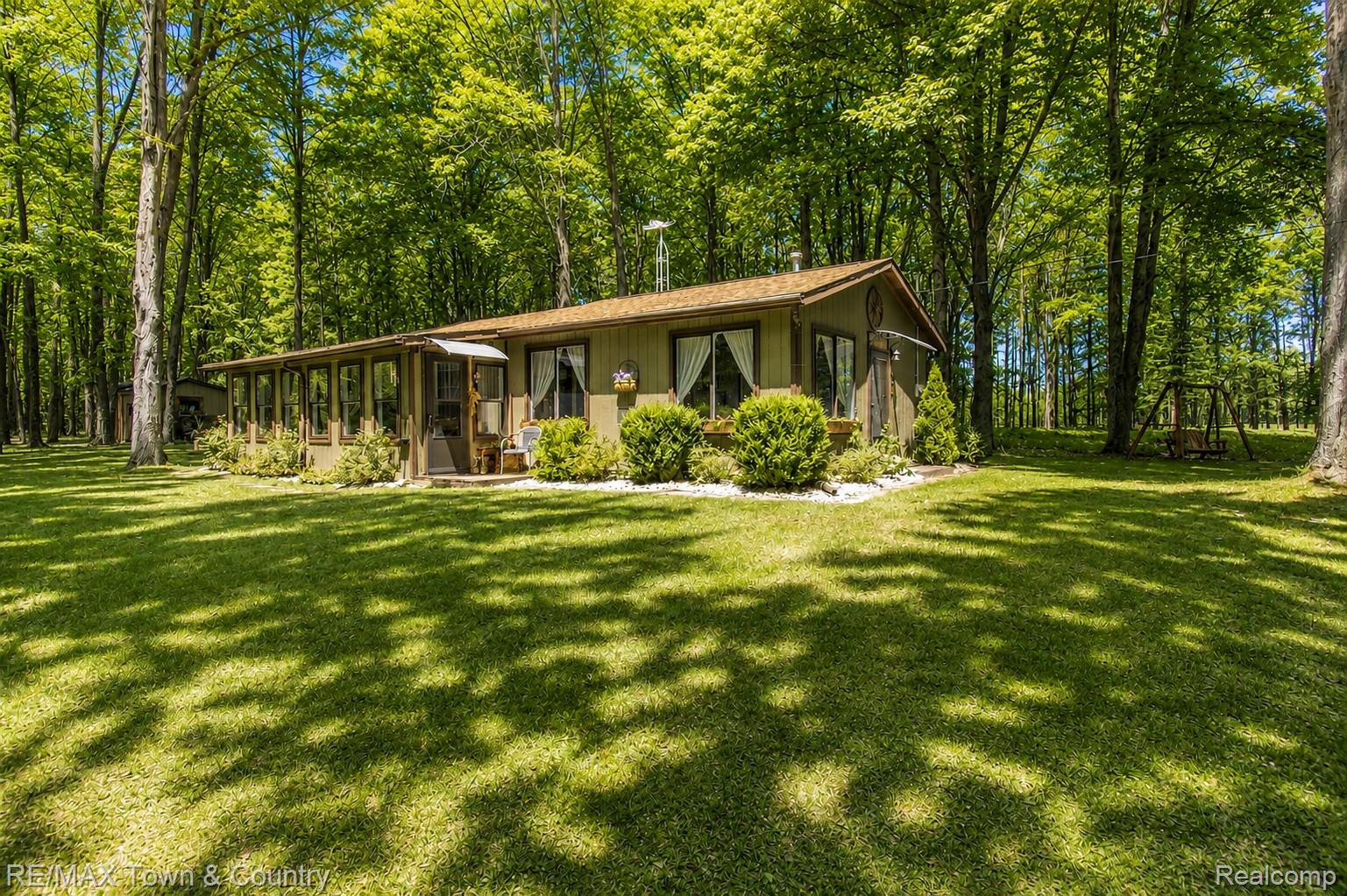 1293 Bellinger Road Gladwin, MI 48624 - Photo 18 of 27 Wooded surroundings with mature trees, expansive lawn, enclosed sunroom, and established landscaping
