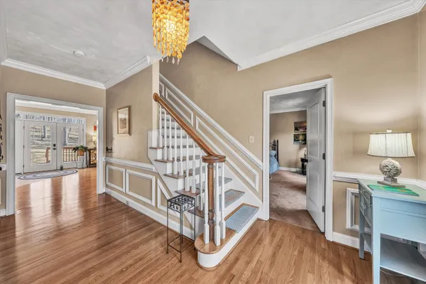 a dining room with wooden floor a rug and a chandelier