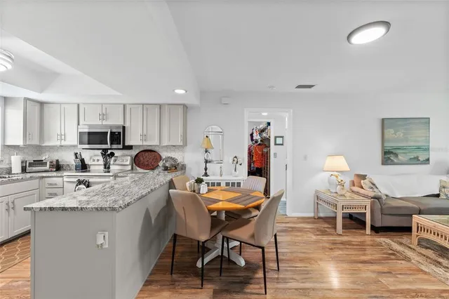 a kitchen with stainless steel appliances granite countertop a table chairs sink refrigerator and cabinets