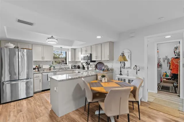 a kitchen with stainless steel appliances kitchen island granite countertop a dining table and chairs