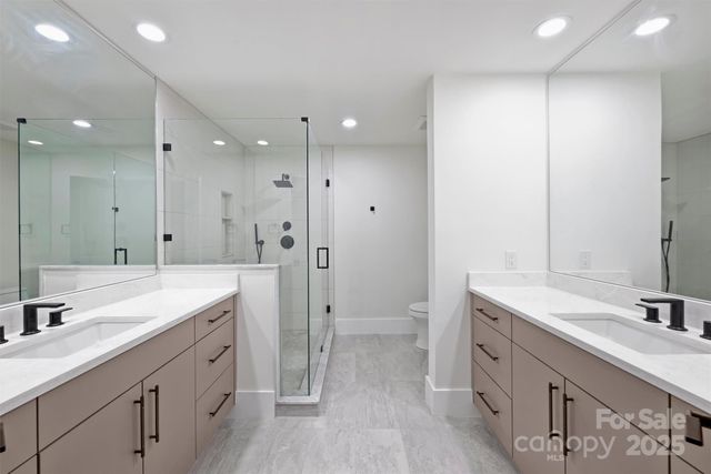 a spacious bathroom with a double vanity sink toilet mirror and hardwood