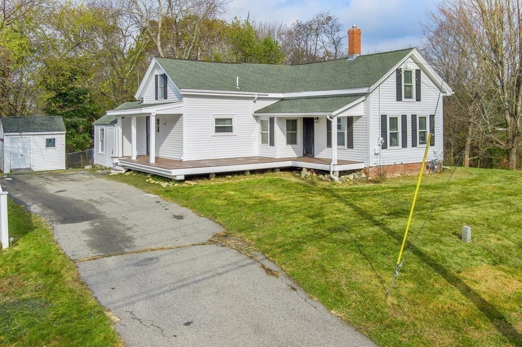 a view of a white house with a big yard and potted plants