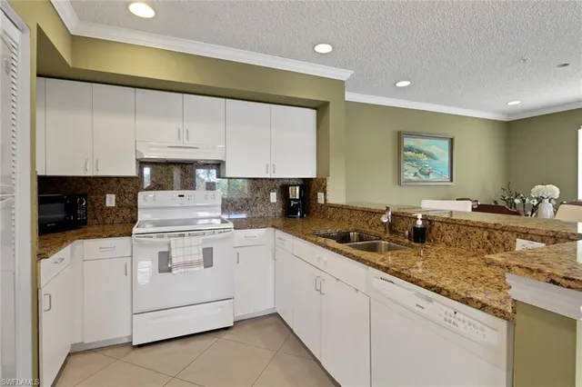 a kitchen with granite countertop white cabinets and white appliances