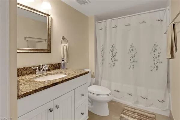 a bathroom with a granite countertop sink a toilet and a mirror
