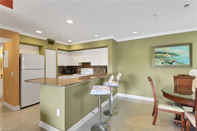 a living room with stainless steel appliances furniture a dining table and kitchen view