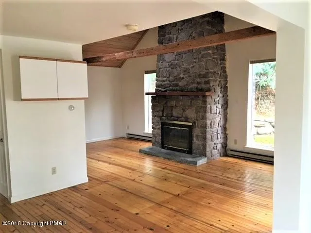 a view of empty room with wooden floor and fireplace