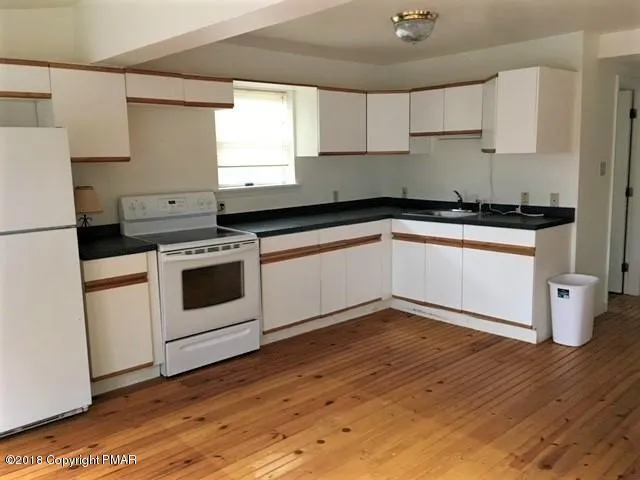 a kitchen with granite countertop wooden floors and white stainless steel appliances