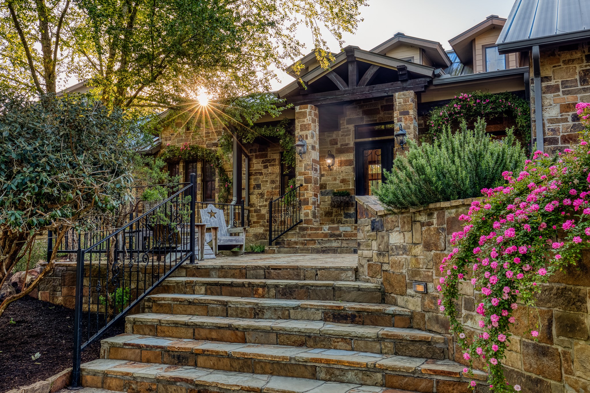 a view of house with large trees and flower plants