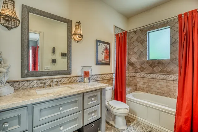 a bathroom with a granite countertop toilet sink and mirror
