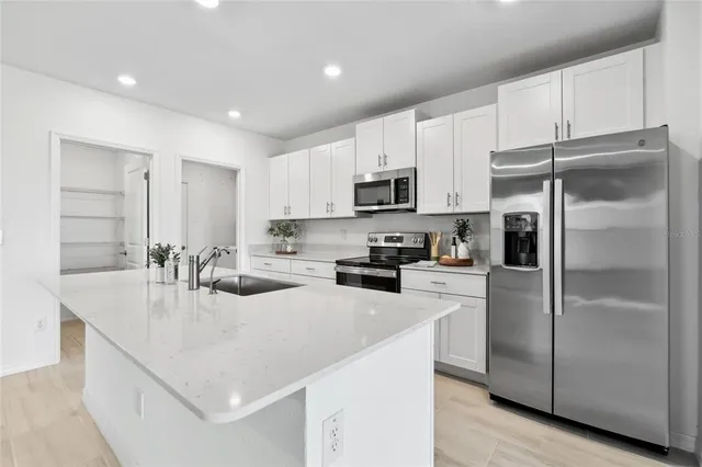 a large kitchen with stainless steel appliances granite countertop a stove a refrigerator a sink and a granite counter tops