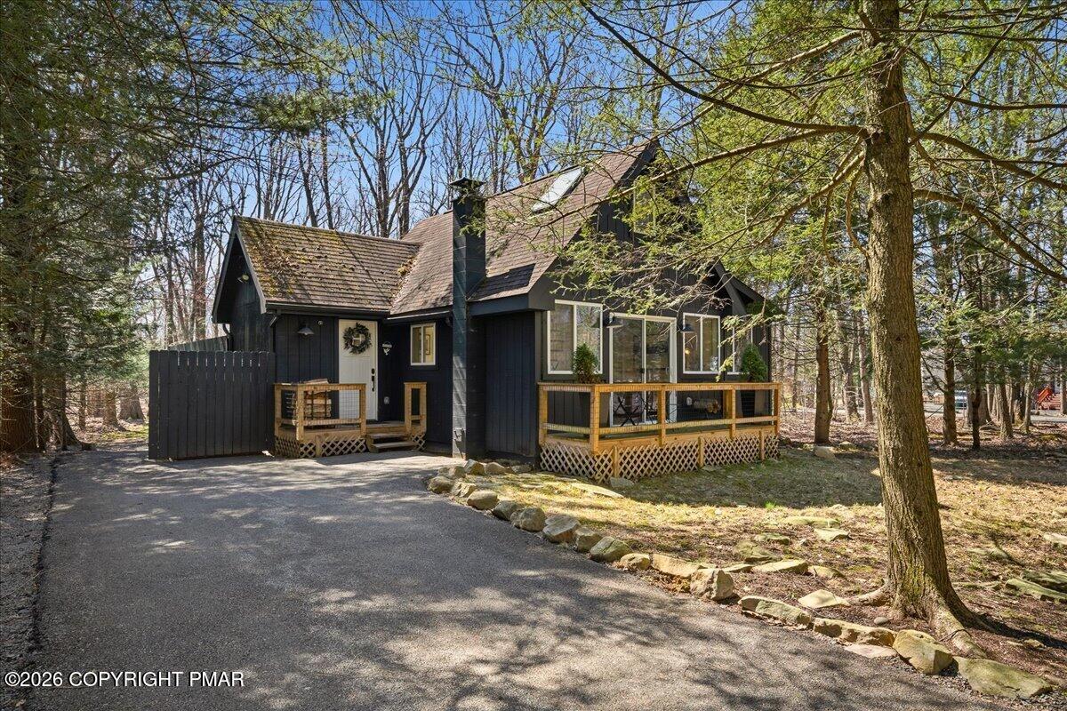 a view of a house with large trees and a wooden fence