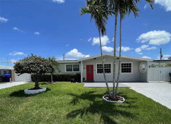 a front view of a house with garden and a tree