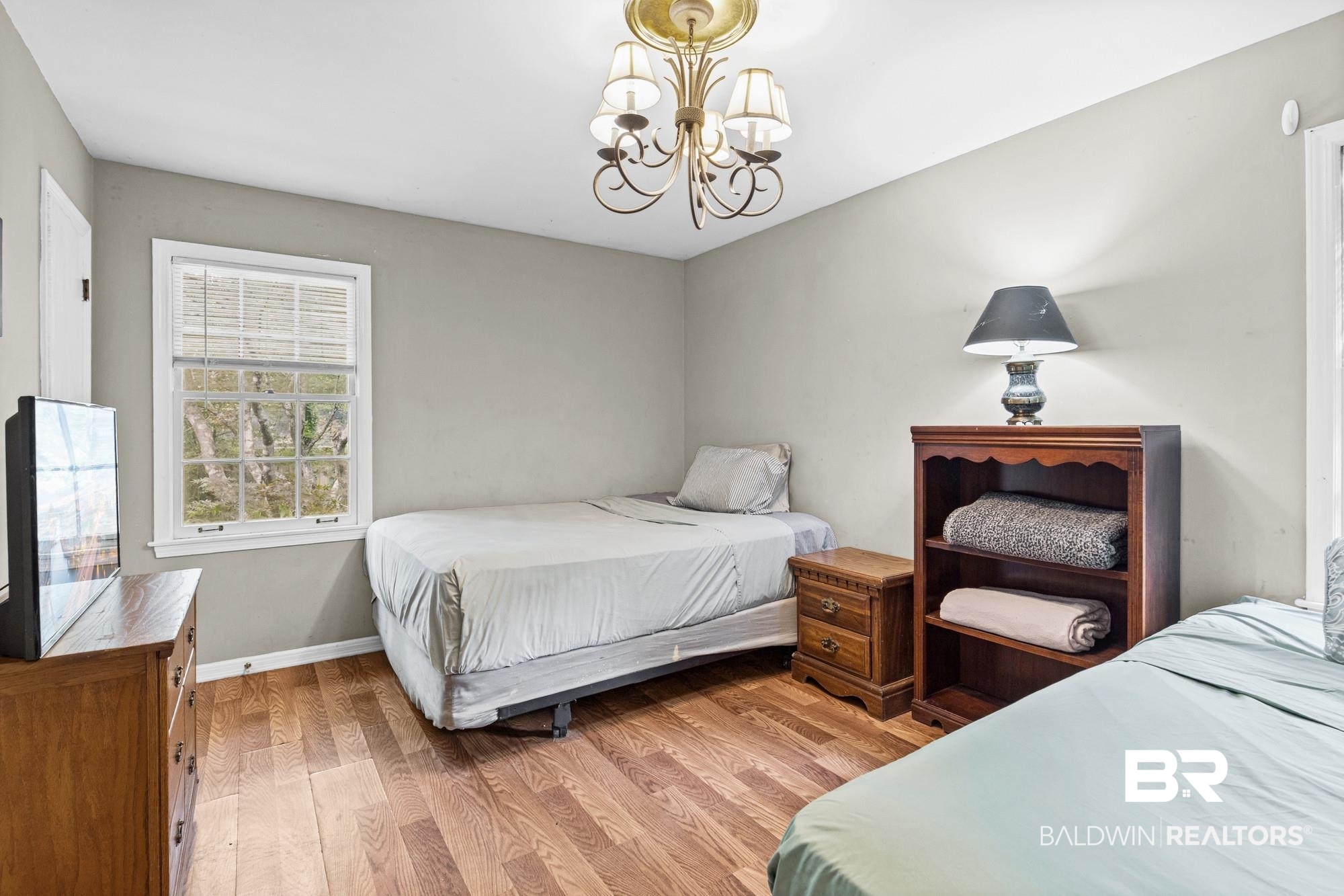 5510 Richmond Road Mobile, AL 36608 - Photo 8 of 21 Spacious room featuring wood-finish flooring, a window with natural light, neutral wall tones, and a decorative ceiling fixture