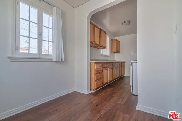 an empty room with wooden floor cabinet and windows
