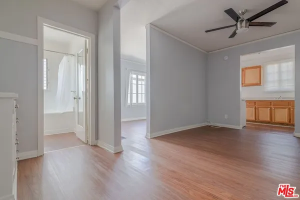 a view of an empty room with wooden floor and a window