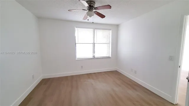 an empty room with chandelier fan and windows