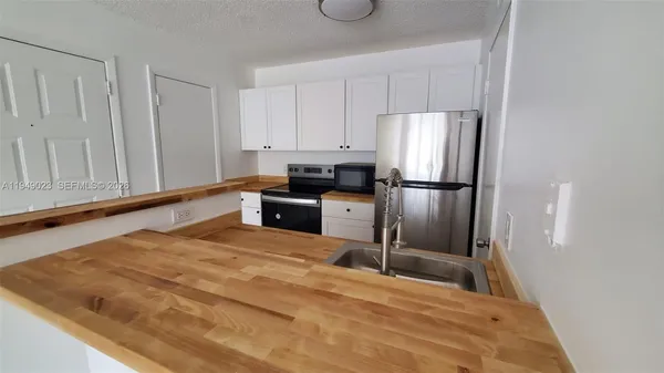 a kitchen with granite countertop a refrigerator sink and cabinets