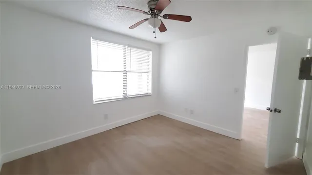 an empty room with windows and fan