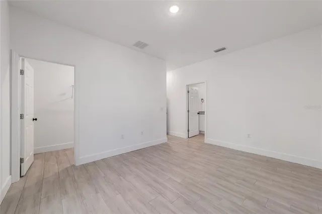 a view of an empty room with wooden floor and closet