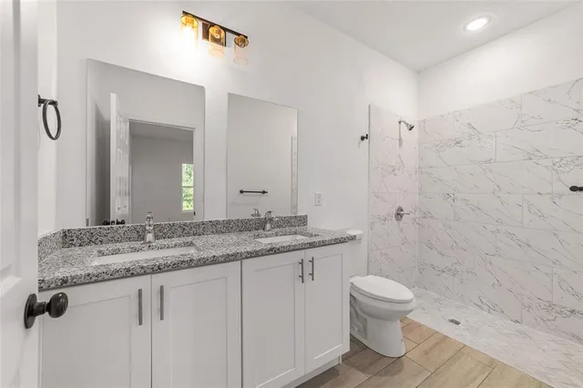 a bathroom with a granite countertop sink a toilet and a mirror