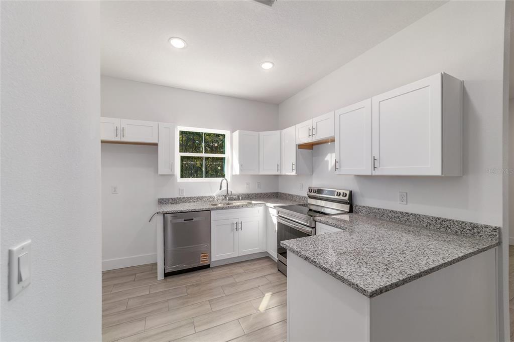 15431 Southwest 41st Street Road Ocala, FL 34481 - Photo 10 of 44 a kitchen with stainless steel appliances granite countertop a sink stove and cabinets
