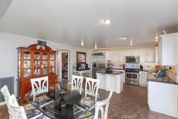 a kitchen with stainless steel appliances kitchen island granite countertop a sink stove refrigerator and cabinets