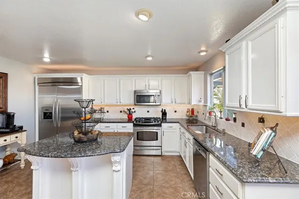a kitchen with stainless steel appliances kitchen island granite countertop a stove top oven a sink a dining table and chairs with wooden floor