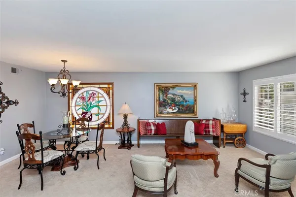 a living room with furniture a dining table and a chandelier