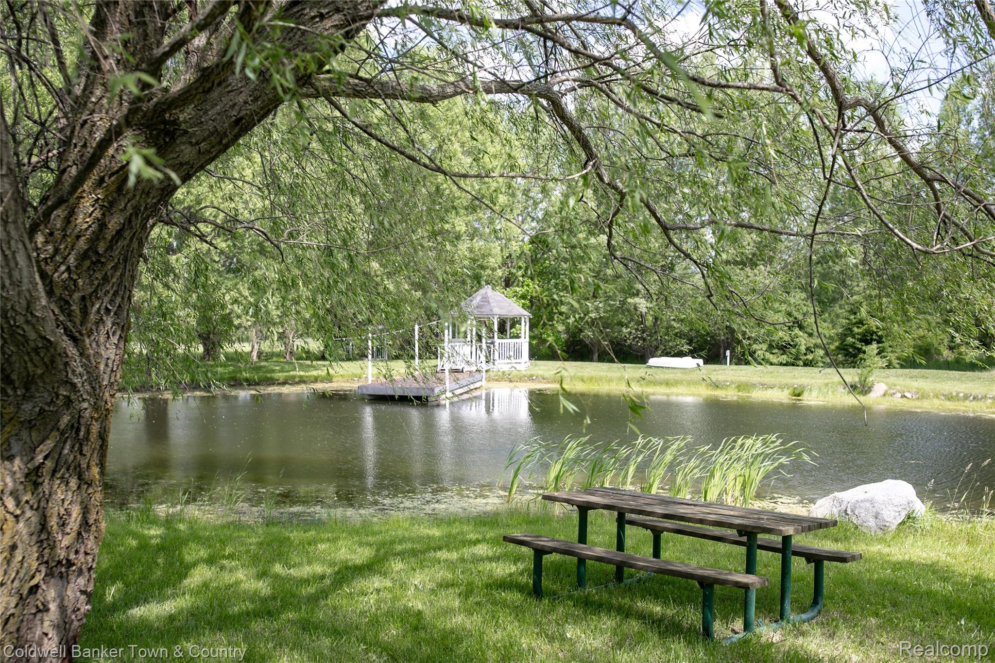 717 North Youngs Road Attica, MI 48412 - Photo 7 of 87 Private pond featuring a dock with a gazebo, surrounded by mature trees and manicured lawn
