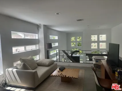 a living room with furniture flat screen tv and windows