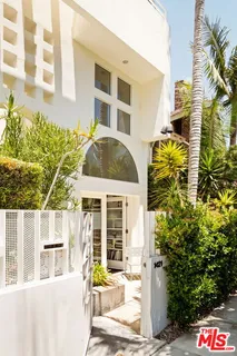 a front view of a building with a garden and plants