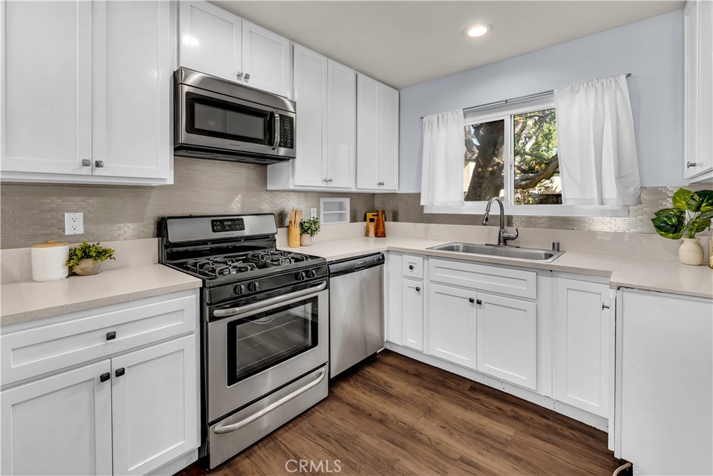 a kitchen with stainless steel appliances white cabinets granite counter tops and a window