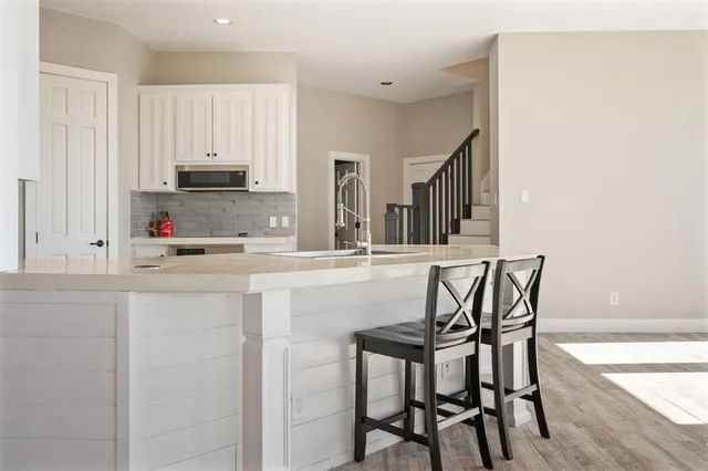 a kitchen with stainless steel appliances kitchen island granite countertop a dining table chairs and a refrigerator