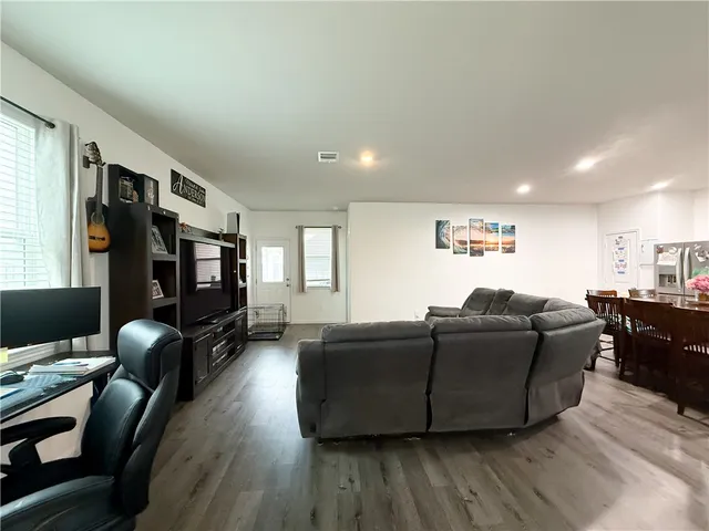 a living room with furniture a flat screen tv and wooden floor