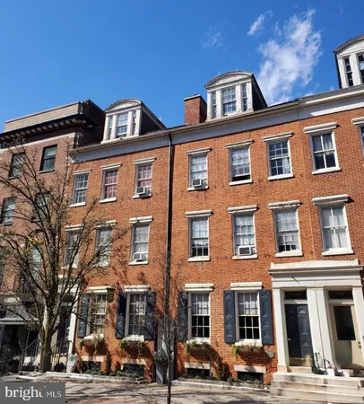 a front view of a building with lot of cars and trees