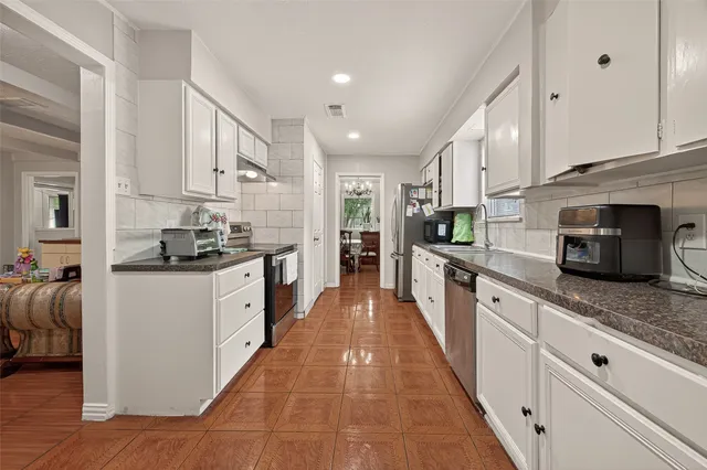 a large white kitchen with stainless steel appliances granite countertop lots of counter top space