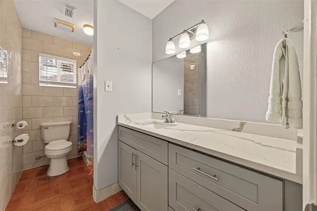 a bathroom with a toilet sink double vanity and mirror
