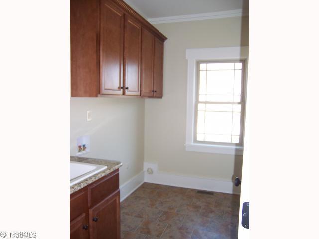 7776 Sutter Road Greensboro, NC 27455 - Photo 14 of 16 Laundry Room. Tiled floor, Laundry sink with Granite countertop, Cabinets for storage over Washer/Dryer area.