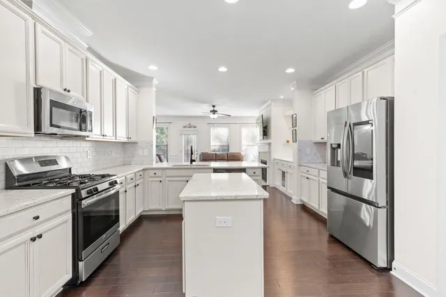 a kitchen with stainless steel appliances kitchen island granite countertop a stove sink and refrigerator