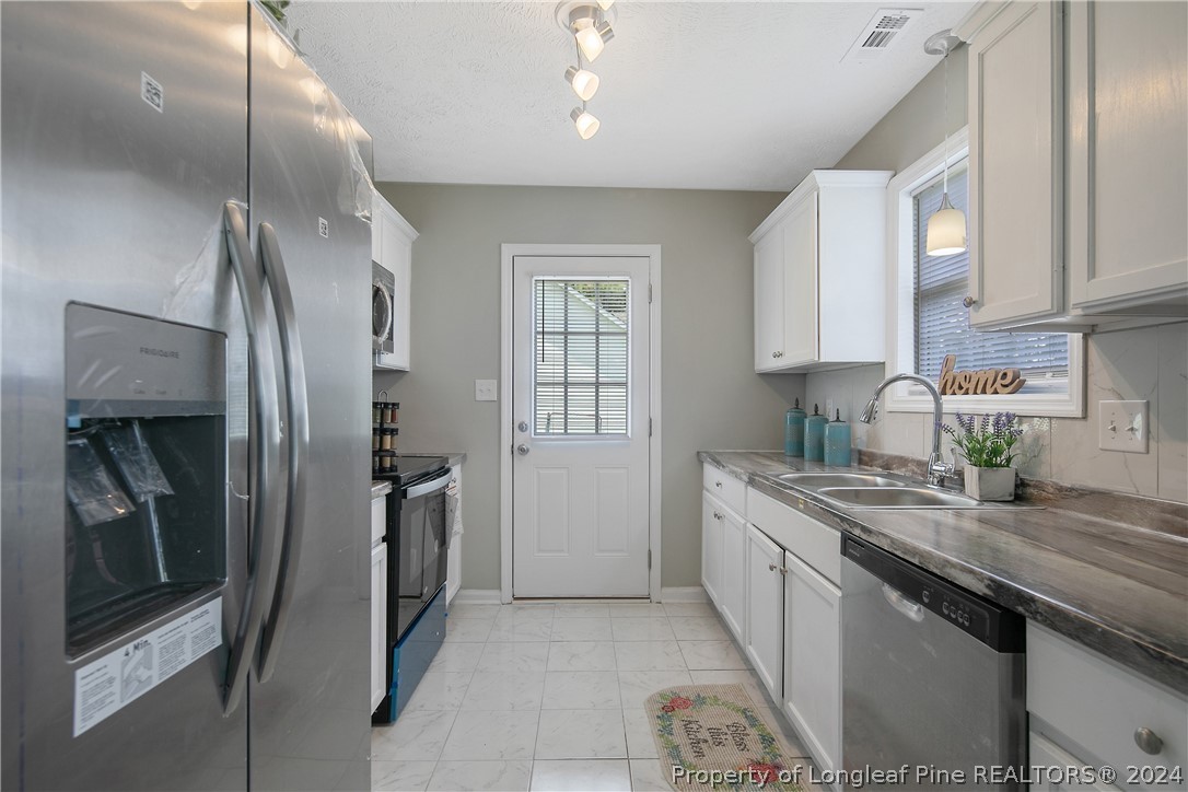130 Rye Lane Raeford, NC 28376 - Photo 13 of 38 a kitchen with stainless steel appliances granite countertop a refrigerator a sink a stove and white cabinets